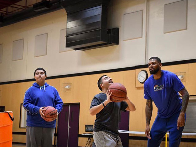 Basketball coach helping player with a shot.